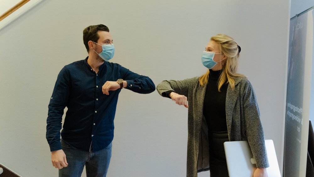 New Partnership - image of a man and woman wearing hospital masks and looking at each other while touching their elbows together