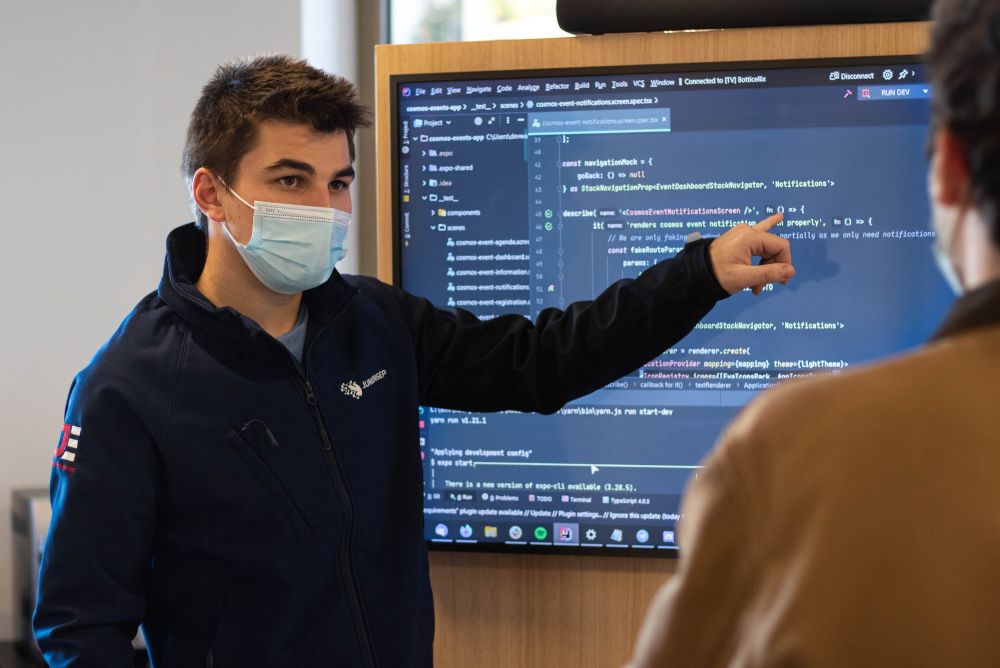 Upskilling jobseekers - image of a young man wearing a hospital mask, pointing to a screen while talking to another man