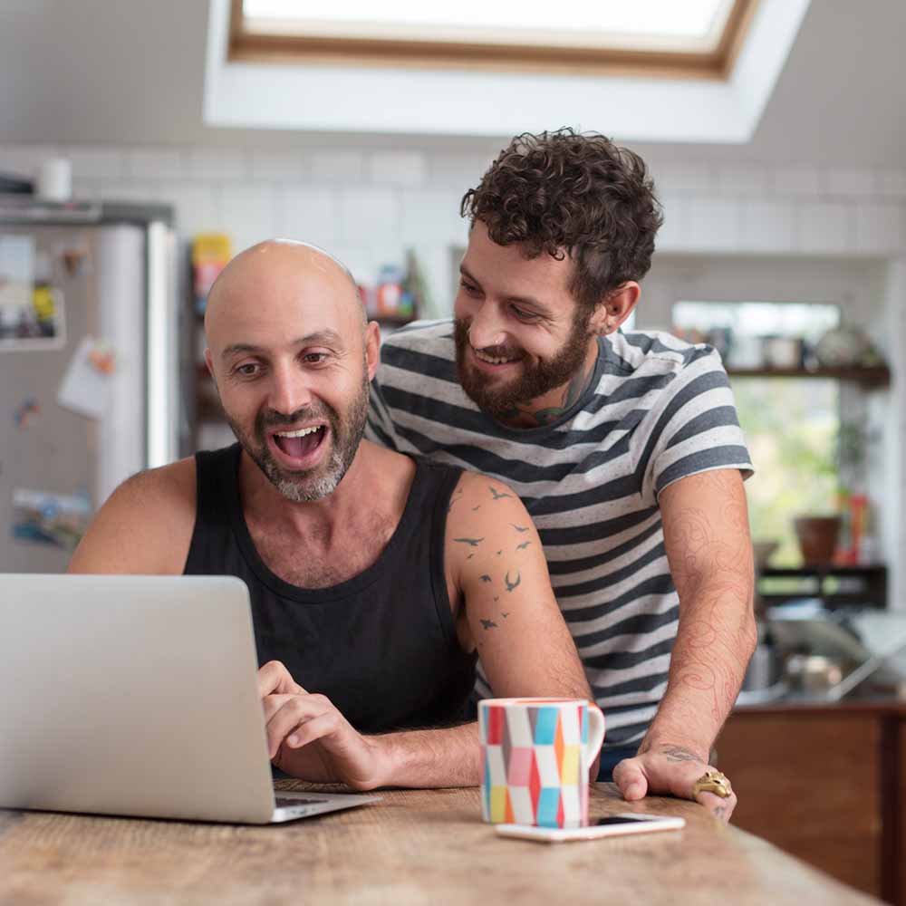 Jobfind LGBTIQ gay couple-image of two men looking at a laptop screen on a table and smiling