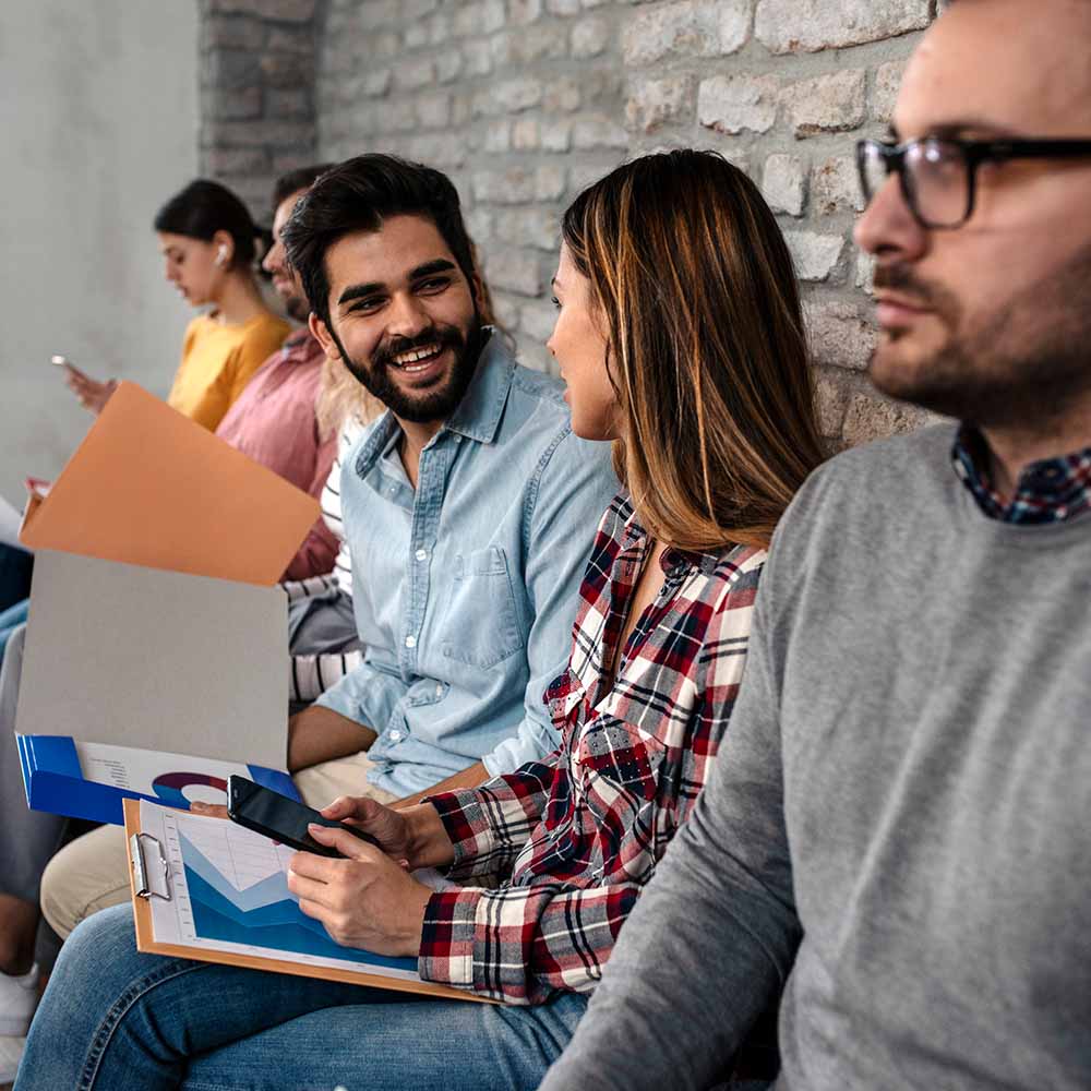 Jobfind FAQ - image of people sitting on a bench against a wall and two are smiling at each other