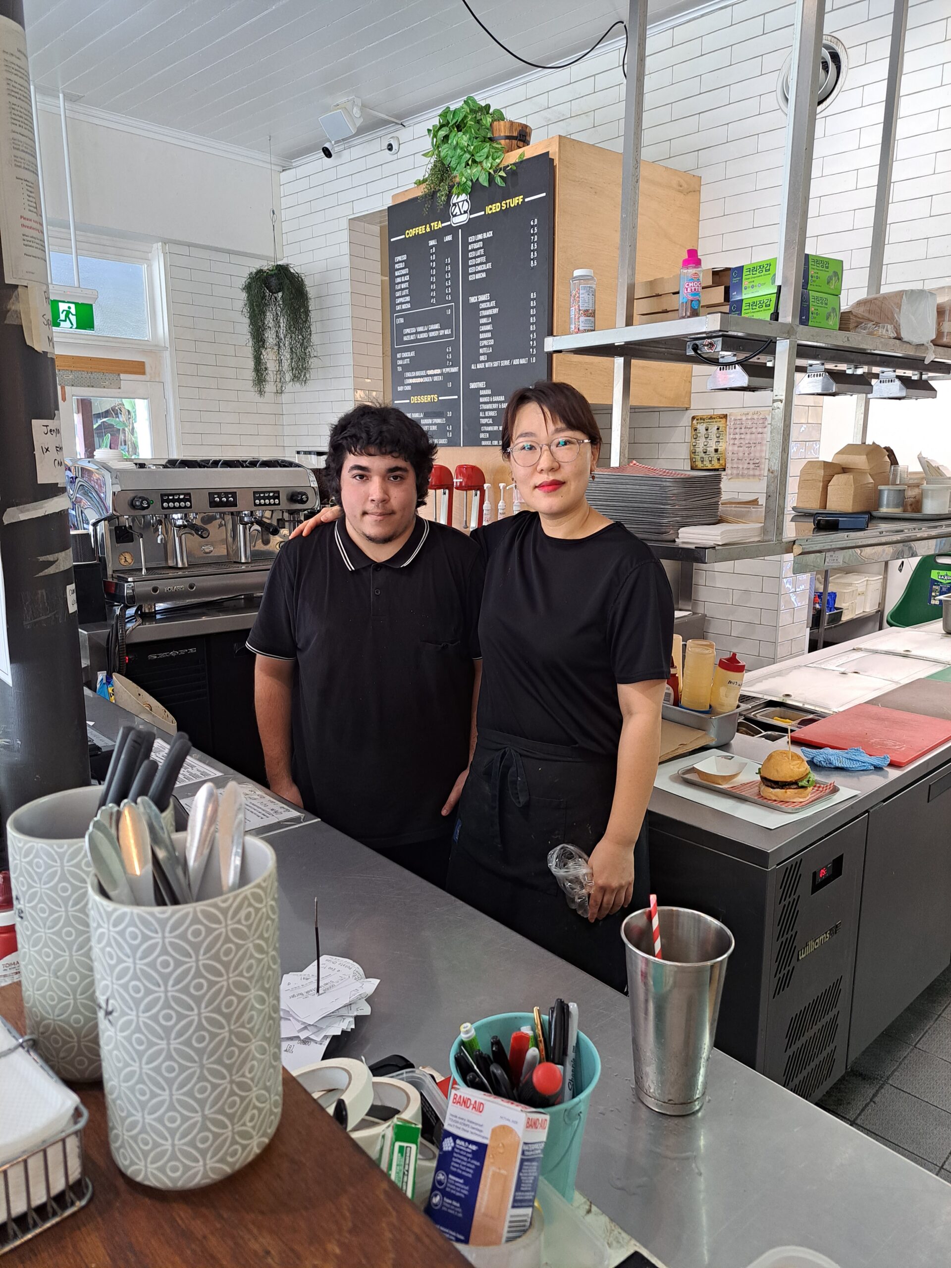 Image of a woman and a newly employed young man standing together facing the camera.